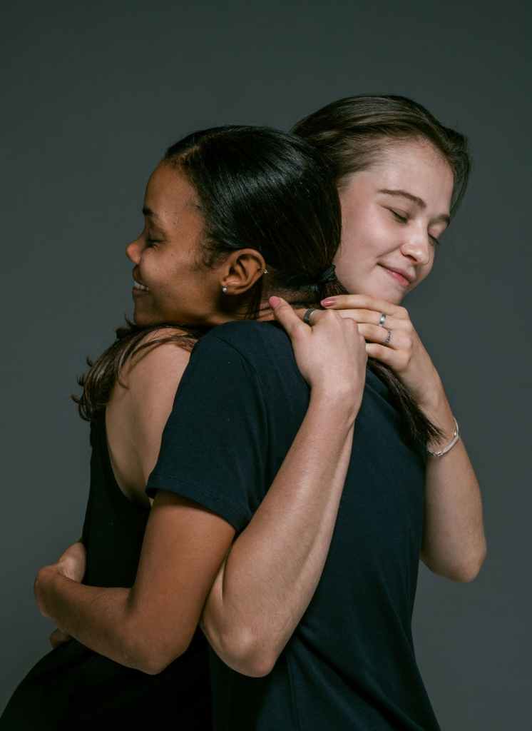 Two women wearing black shirts embrace in a hug. Photo by Ketut Subiyanto on Pexels.com