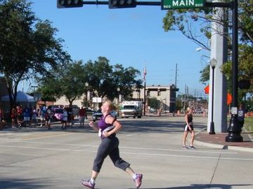 Author running through an intersection reading "main" with crowds cheering along the roadway.